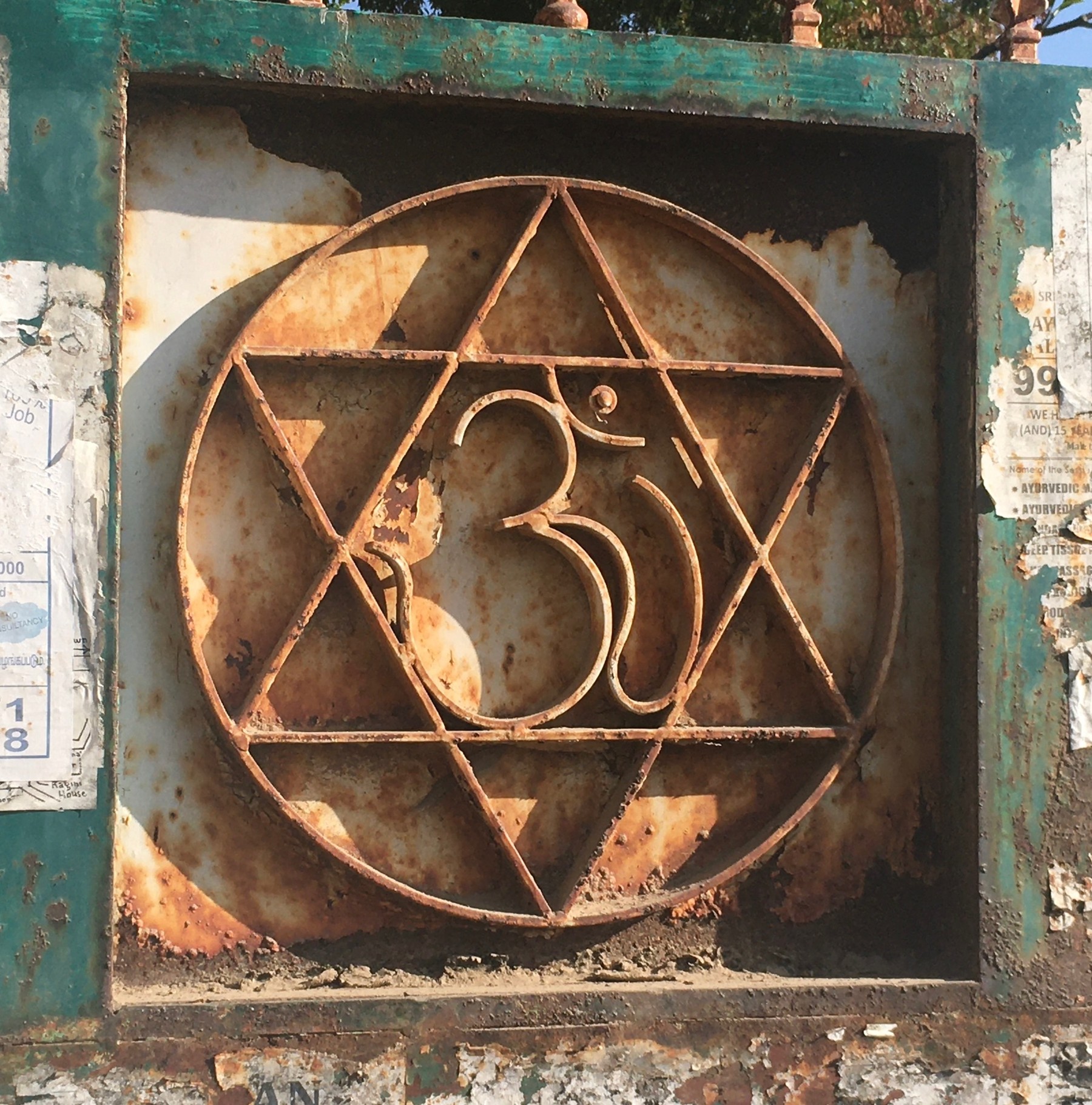 An Om symbol within a circular geometric design on a weathered wall